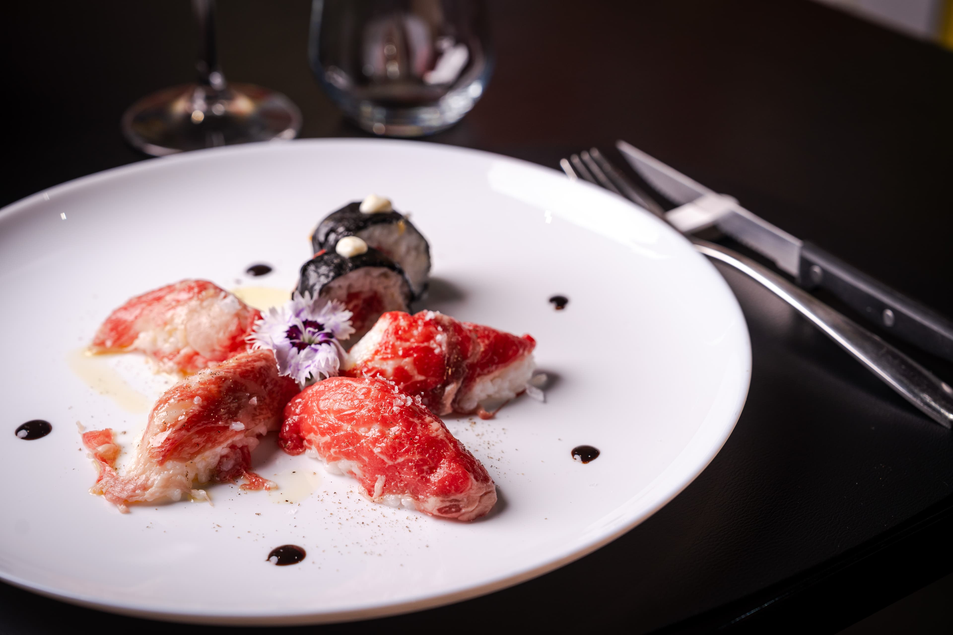 Piatto raffinato con crudo, roll e decorazione floreale