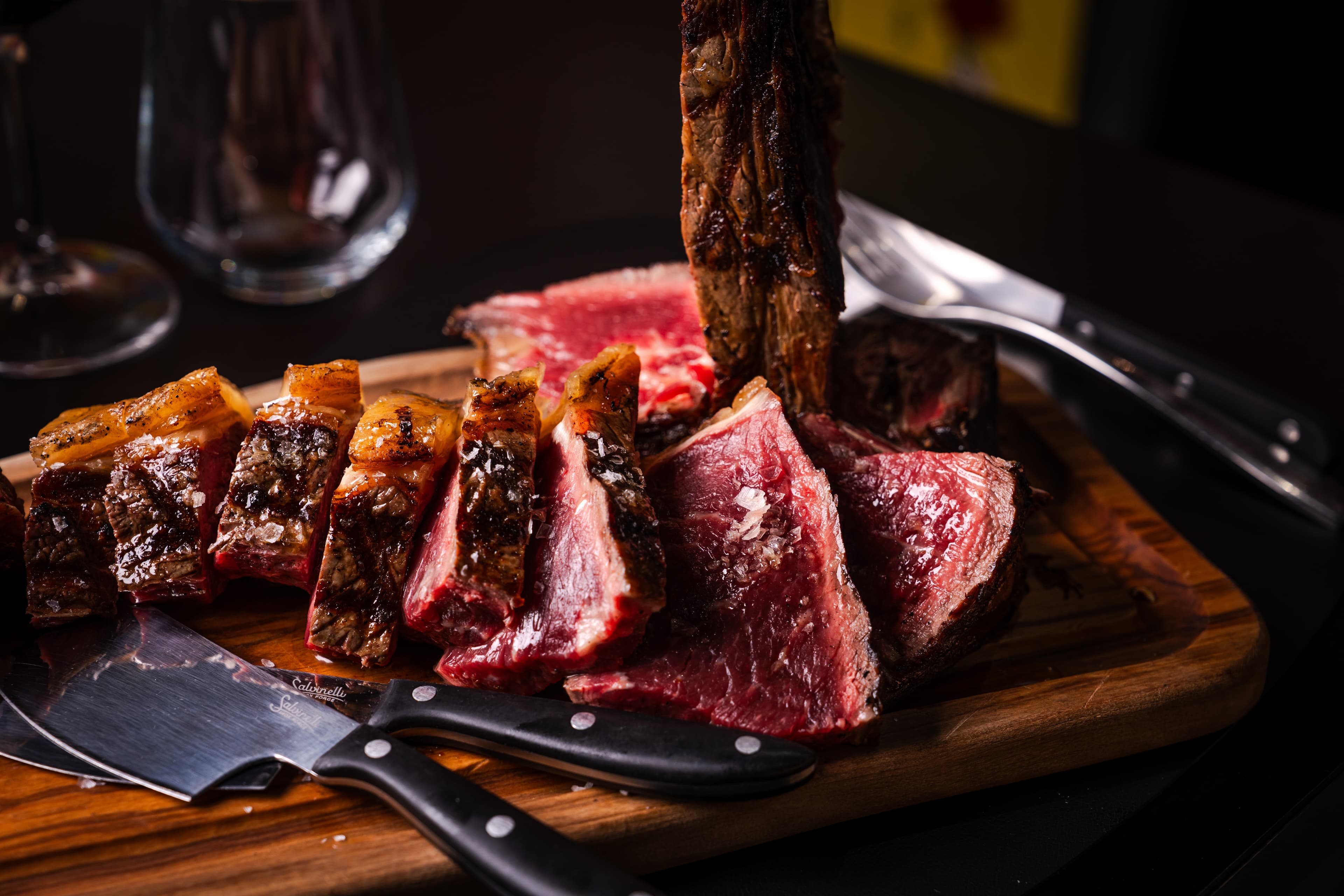 Taglio di carne alla brace servito su tagliere con coltelli