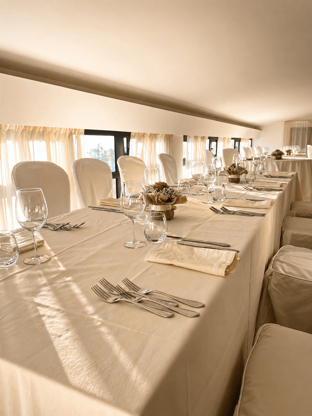 Sala elegante di Brina con tavoli apparecchiati, calici e luce calda